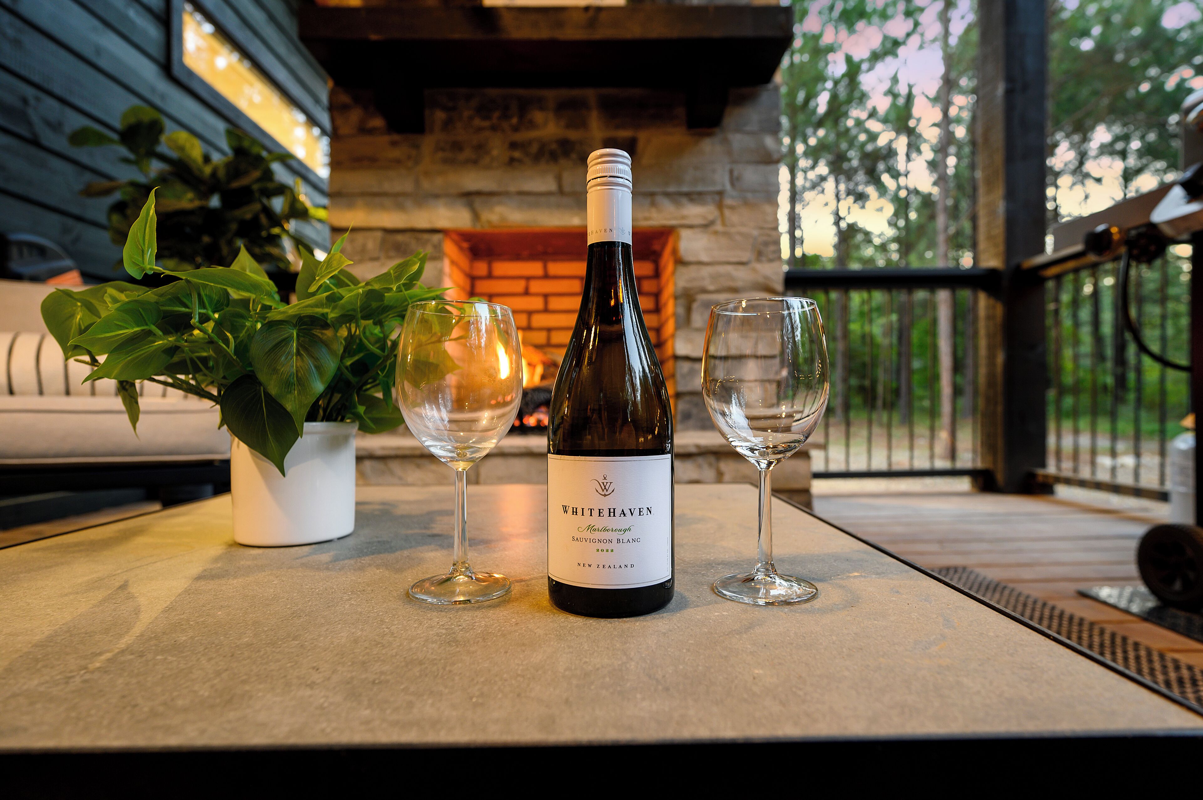 A bottle of Whitehaven Sauvignon Blanc on a table with two empty wine glasses.