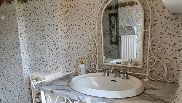A bathroom with a white marble sink, a large mirror, and decorative wall tiles.