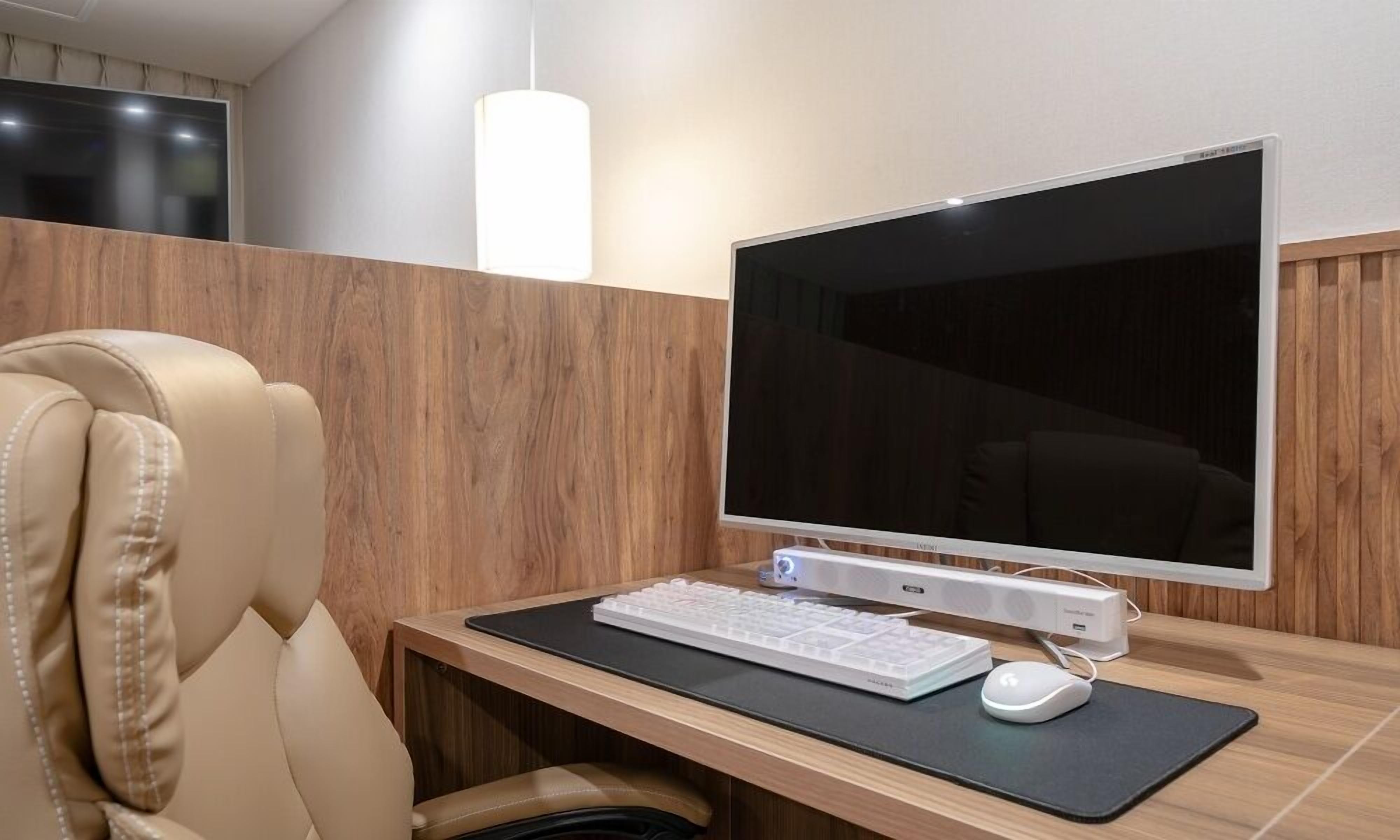 Un espace de bureau moderne, doté d’un grand écran, d’un clavier et d’une souris sur un bureau.