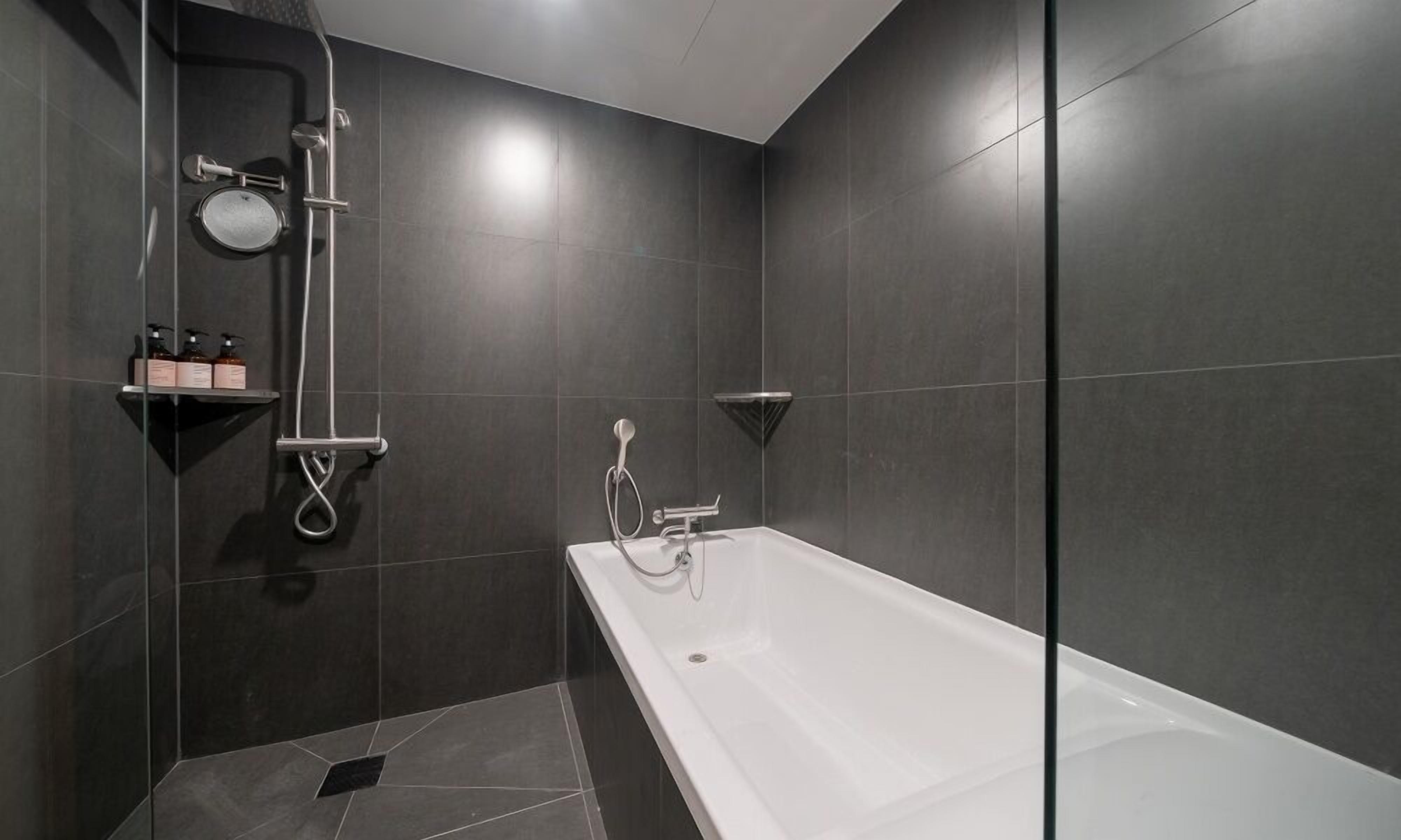 Un baño moderno con bañera, ducha y un estante con artículos de aseo.
