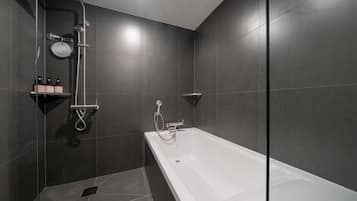 Un baño moderno con bañera, ducha y un estante con artículos de aseo.