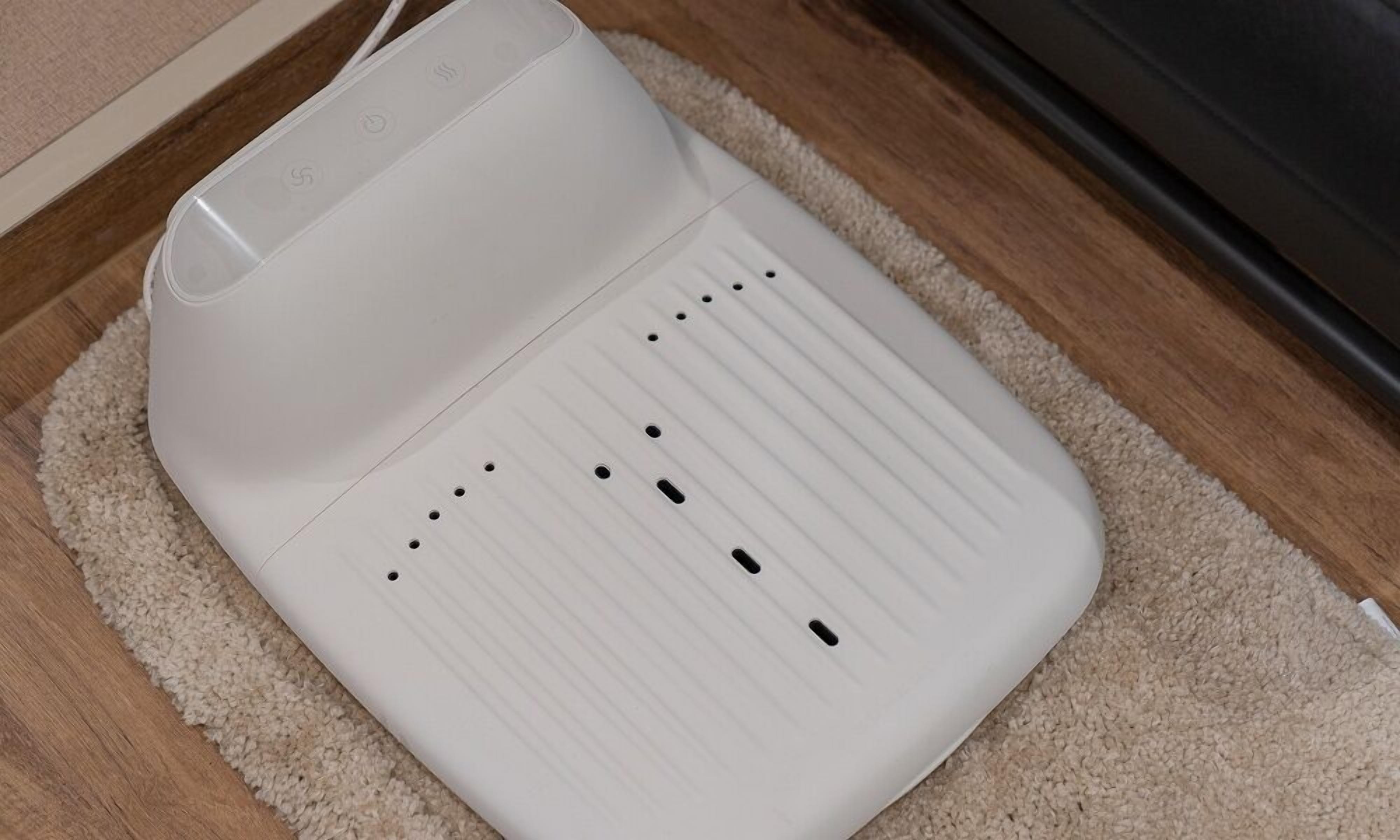 A white electronic device with multiple ports on a beige carpet.