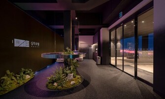 Un interior moderno con una recepción, un pequeño jardín interior y una puerta de vidrio que da al exterior.
