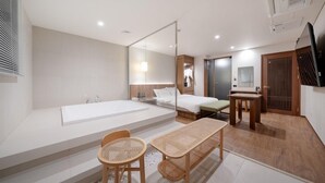 A modern hotel room with a large bathtub, a bed, a small table, and a seating area with woven chairs. - Simjak Hotel Dongtan By Anook (Hwaseong)