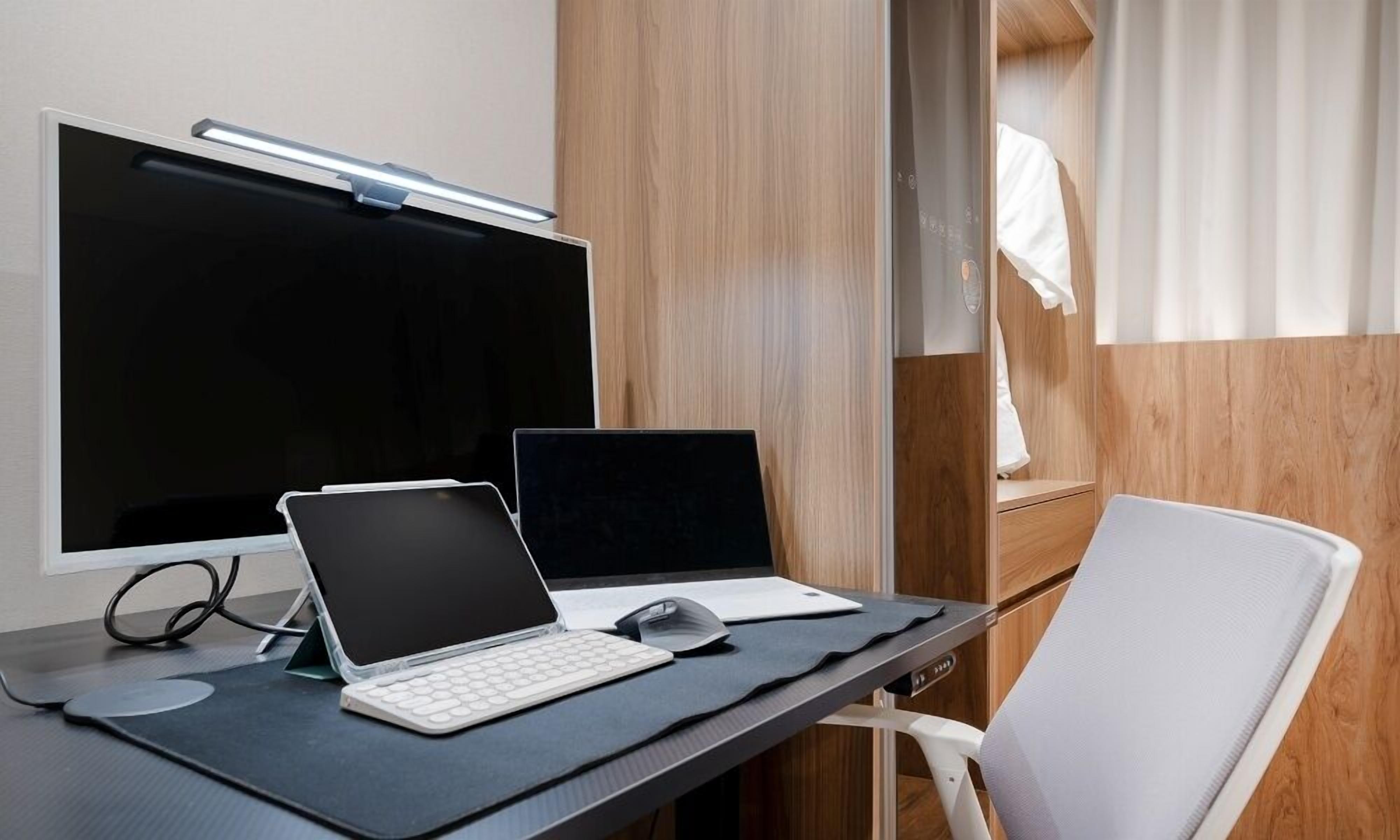 Un espacio de trabajo moderno con un escritorio, dos computadoras portátiles, un monitor de ordenador y un teclado.