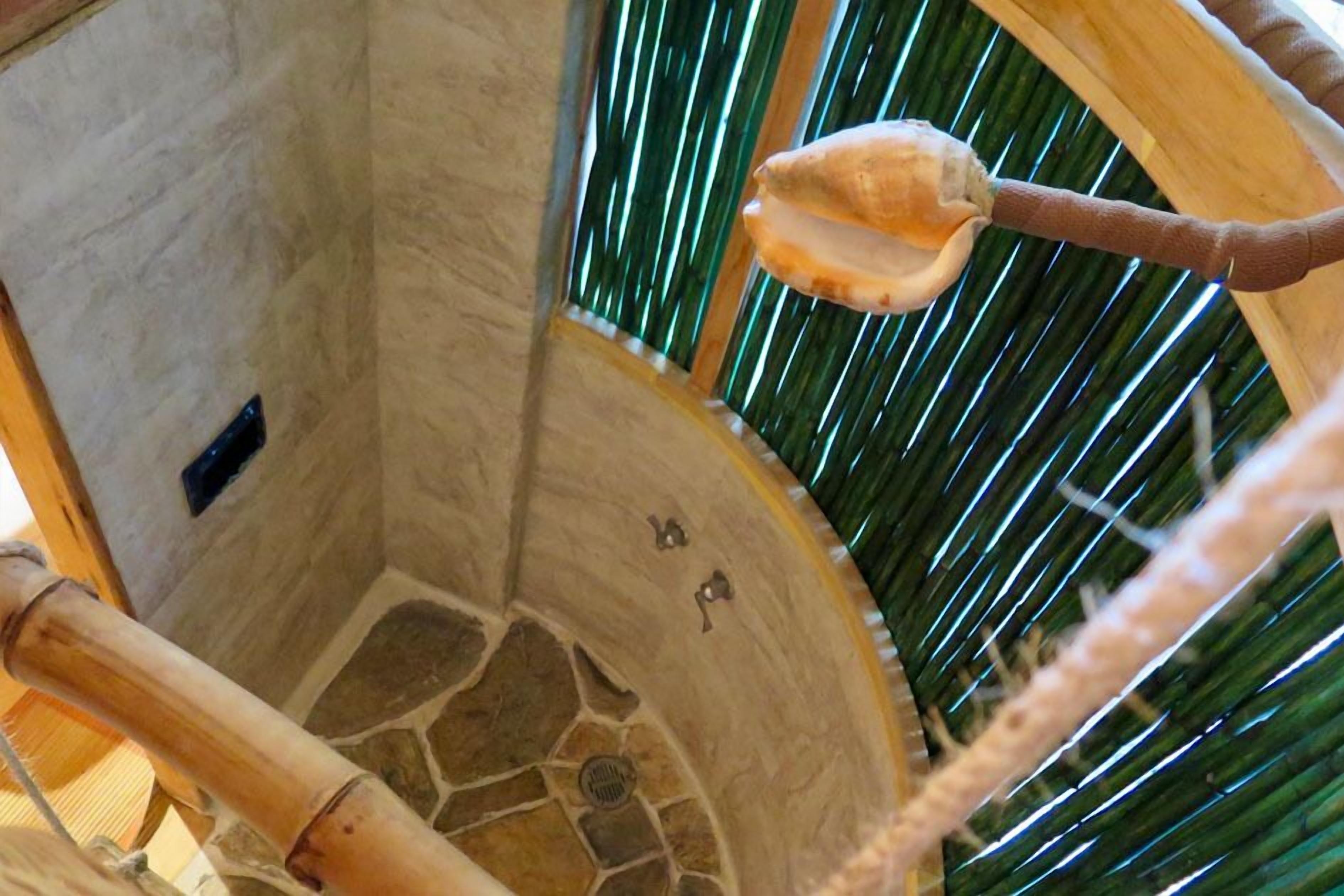 A spiral staircase with a stone wall and a palm tree in the background.
