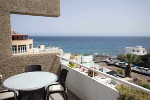 Varanda com mesa e cadeiras com vista para uma área costeira com barcos e edifícios.