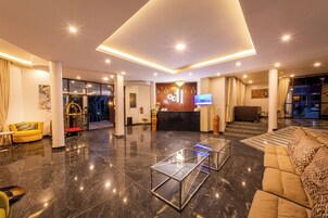 Un moderno vestíbulo de hotel con mostrador de recepción, zonas de estar y una mesa de centro de vidrio.