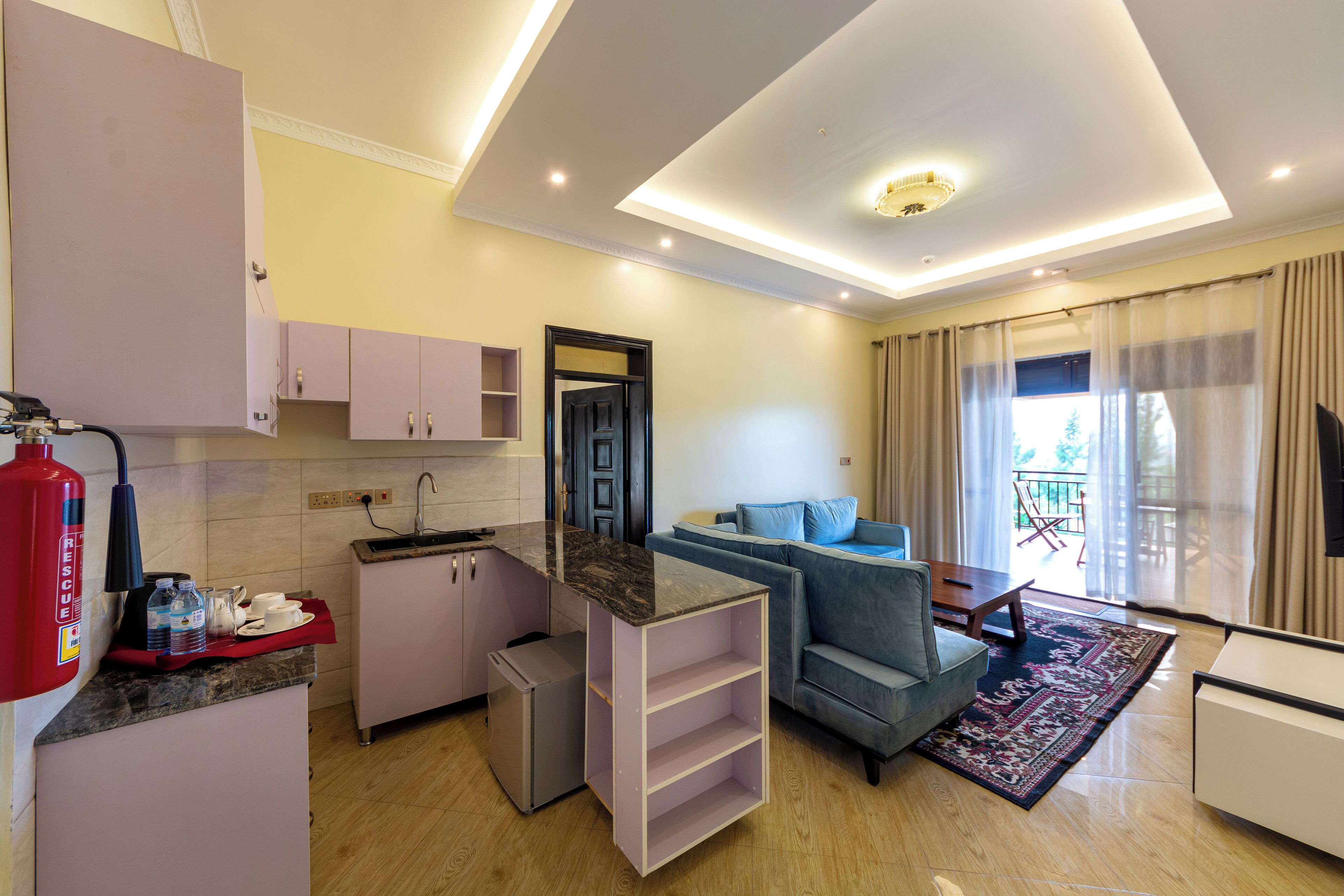 A compact living space with a kitchenette, a sofa, a coffee table, and a view of the outdoors.