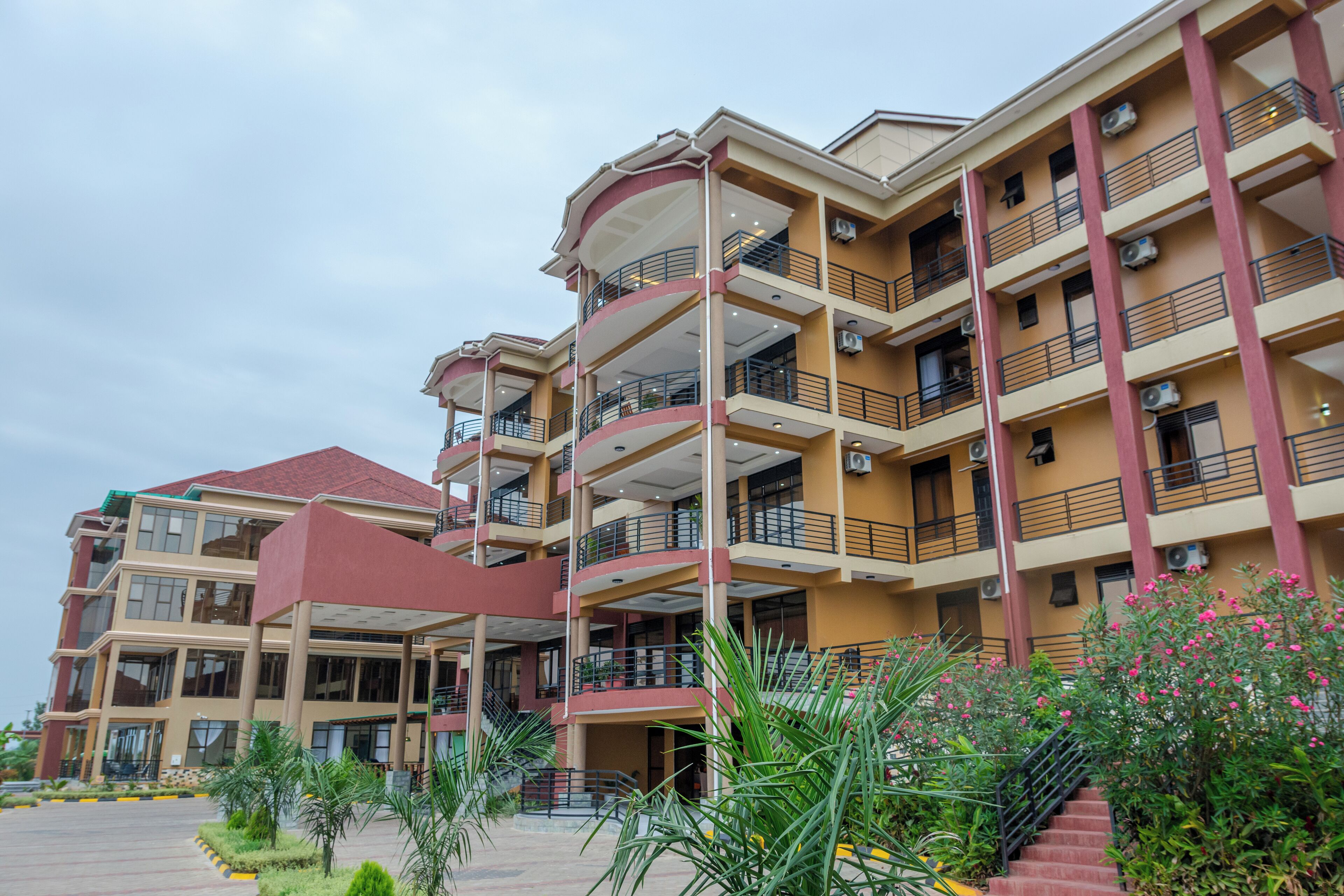 A multi-story hotel with balconies, a central courtyard, and a red-roofed building.