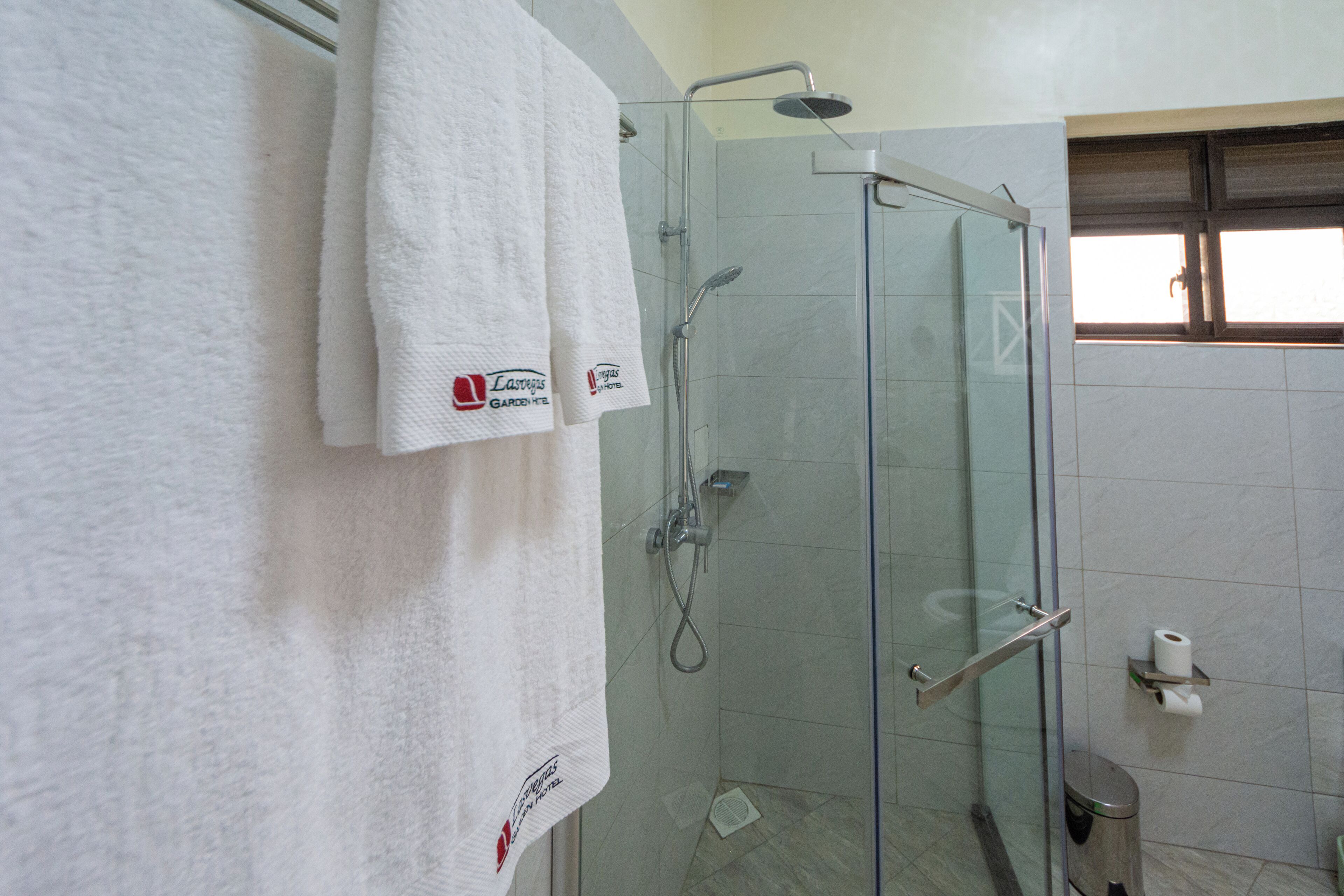 A glass-enclosed shower with a handheld showerhead and a handheld faucet.