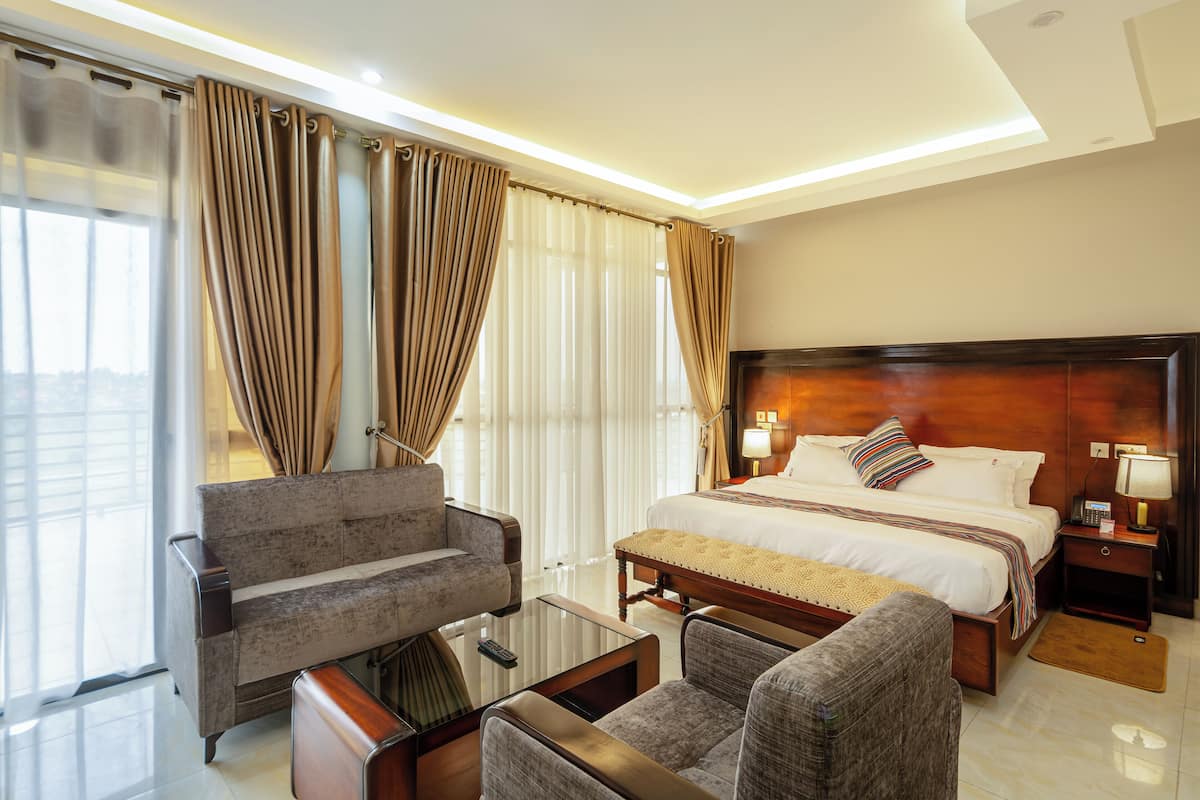 Una habitación de hotel con una cama grande, un sofá, una mesa de centro y un escritorio con una lámpara.