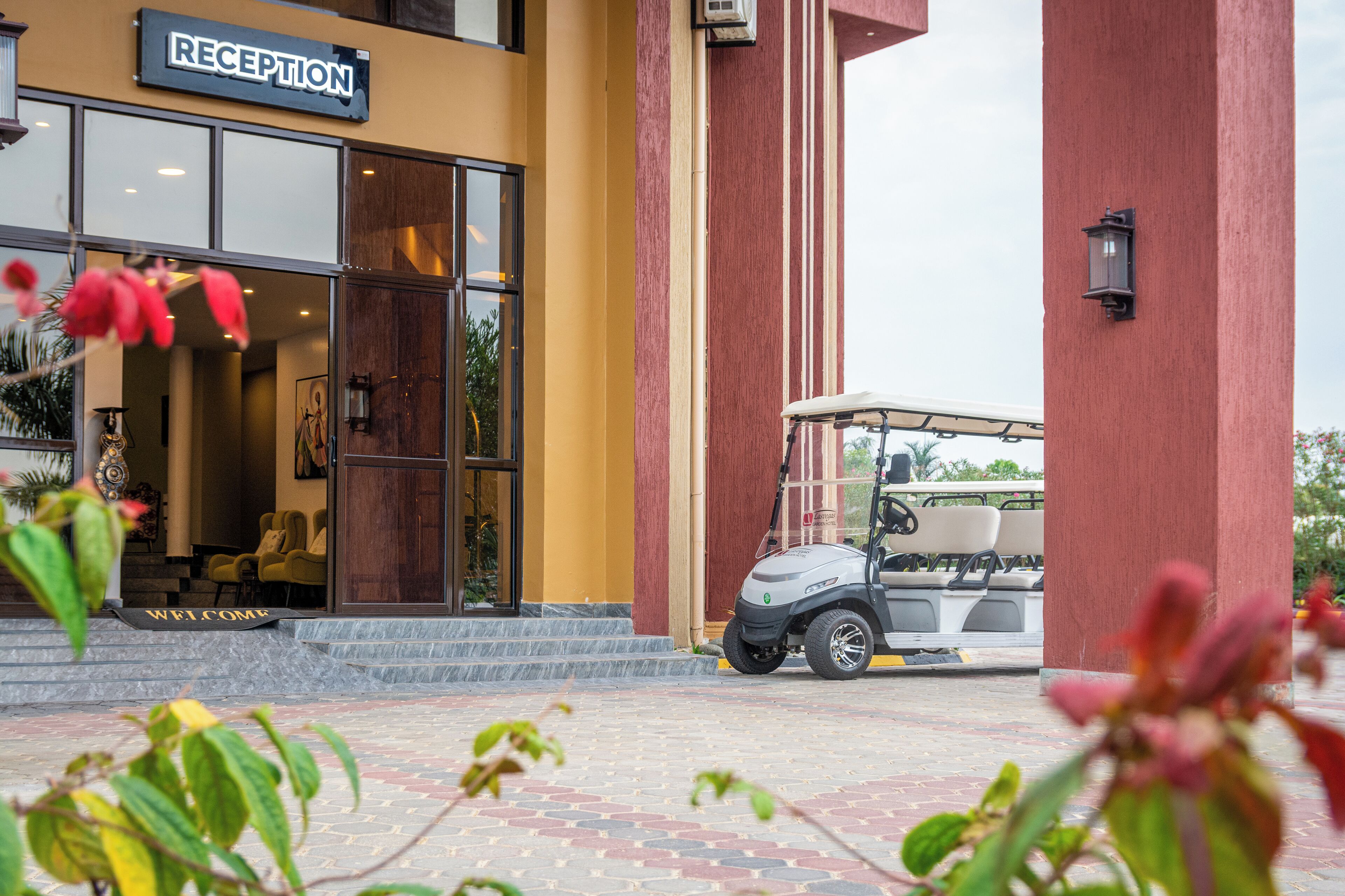 A reception area with a golf cart parked outside, a welcome mat, and a building with a reception sign.