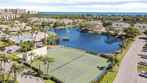 Zona residencial con cancha de tenis, piscina y una masa de agua.
