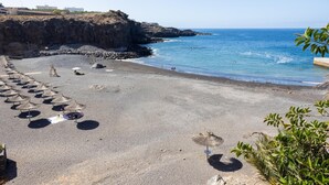 A beach with umbrellas and a rocky cliff. - Cozy Apartment with Sea Views in Costa Adeje (Adeje)