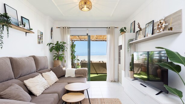 A modern living room with a sofa, a TV, and a balcony with a view of the sea. - Cozy Apartment with Sea Views in Costa Adeje (Adeje)