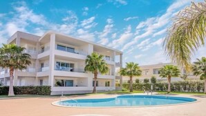 A modern multi-story building with a pool area, palm trees, and a clear sky. - Luxury Apt. Garden, Pool and Near Beach (Lagos)