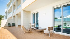 A modern outdoor patio with wicker furniture and a glass door leading to a balcony. - Luxury Apt. Garden, Pool and Near Beach (Lagos)