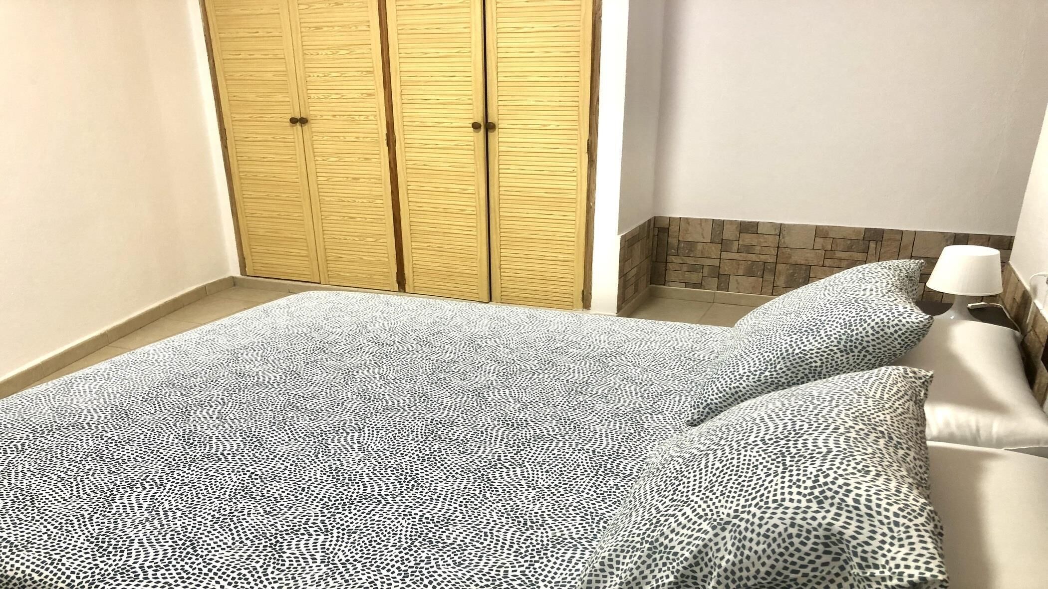 Une chambre à coucher avec un lit, une table de chevet, une lampe et une armoire.