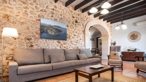 A living room with a stone wall, a sofa, a coffee table, and a lamp. - SES ANGOIXES - Spectacular house in the countryside with private pool and free WiFi (Santanyí)