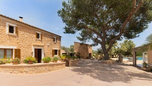 A stone building with a large tree in front, a pool, and outdoor seating. - SES ANGOIXES - Spectacular house in the countryside with private pool and free WiFi (Santanyí)
