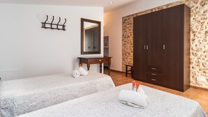A hotel room with two beds, a wooden wardrobe, a mirror, and a small desk. - SES ANGOIXES - Spectacular house in the countryside with private pool and free WiFi (Santanyí)