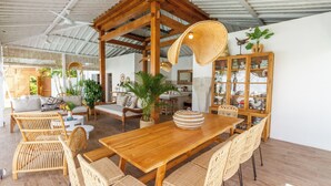 A spacious indoor area with a wooden dining table, wicker chairs, and a ceiling fan. - Villa M2 by Alfred in Bali (Seminyak)