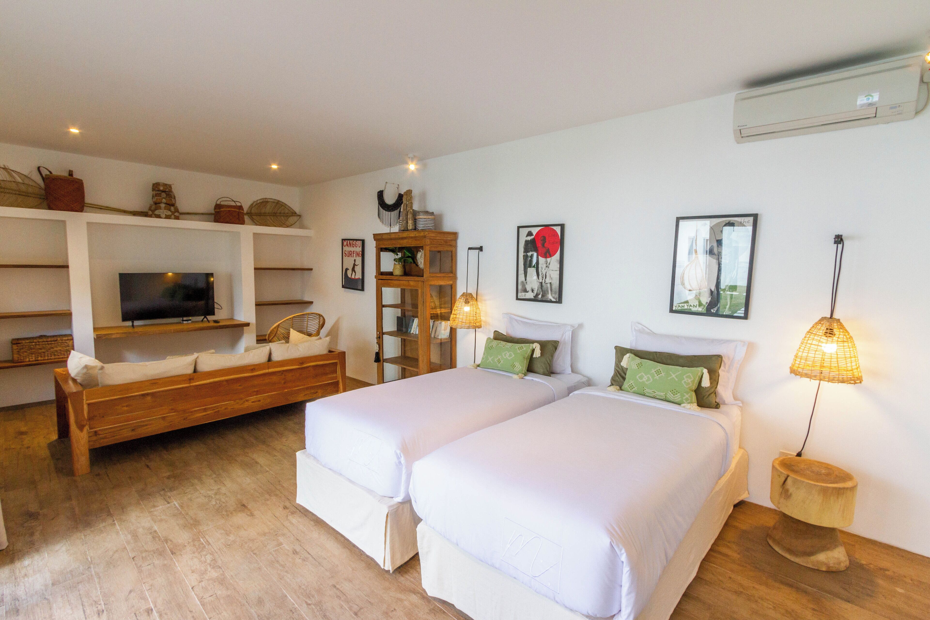 A bedroom with two beds, a TV, shelves with decorative items, and a lamp.