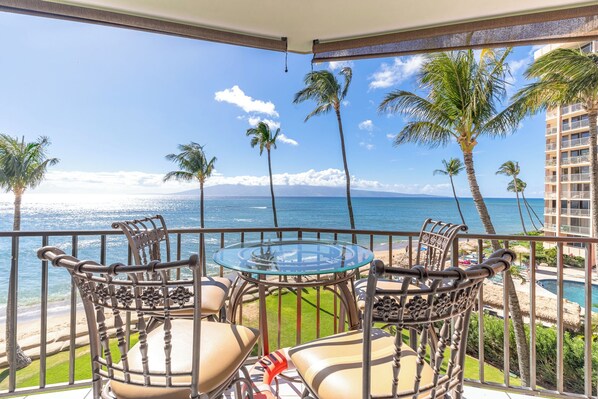 Enjoy breathtaking ocean views from this balcony, featuring a glass-top table and comfortable seating for four.