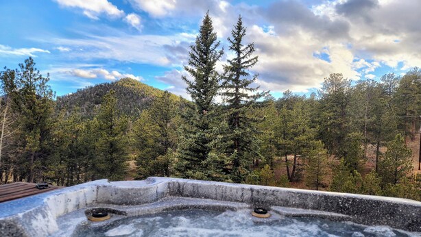A hot tub with a view of a forested hillside. - No Cleaning Fees, Spacious & Secluded Mountain Home, Pikes Peak Views, Hot Tub! (Cripple Creek)
