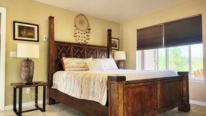 A bedroom with a wooden bed, a nightstand, a lamp, and a wall-mounted dreamcatcher. - No Cleaning Fees, Spacious & Secluded Mountain Home, Pikes Peak Views, Hot Tub! (Cripple Creek)