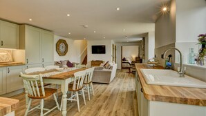 Une cuisine moderne avec une table à manger en bois, des chaises blanches et un évier encastré.