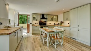 Une cuisine moderne avec un plancher en bois, une table à manger avec des chaises et des meubles de rangement de couleur claire.