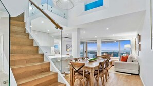 Un interior moderno con una escalera de madera, un comedor con mesa y sillas, y un sofá.