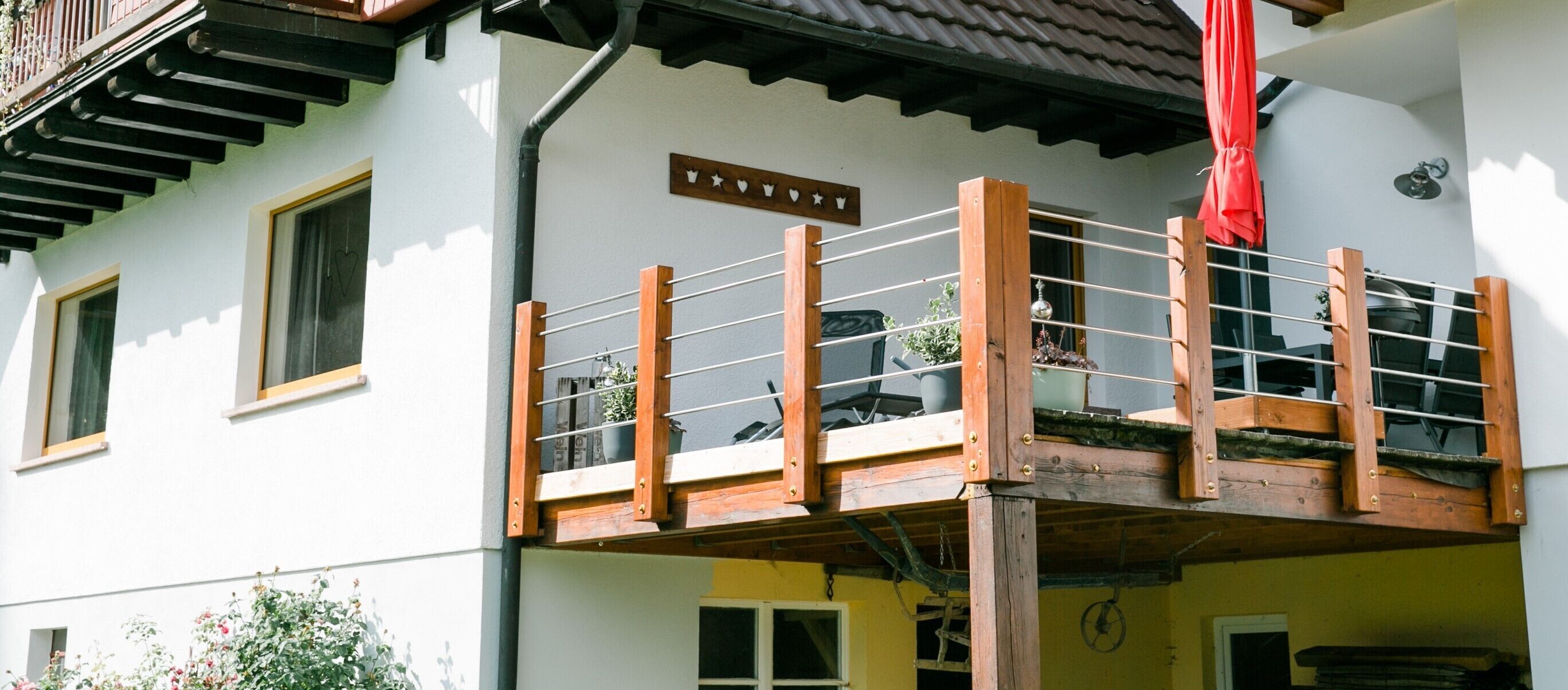 Un edificio a più piani con un balcone, un cartello sopra l'ingresso e un ombrello rosso.