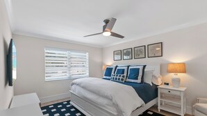 A bedroom with a bed, a nightstand, a lamp, a ceiling fan, and a window with blinds. - RENOVATED 2 Bed, 2 Bath 1st floor with heated pool on the bay! (Naples)