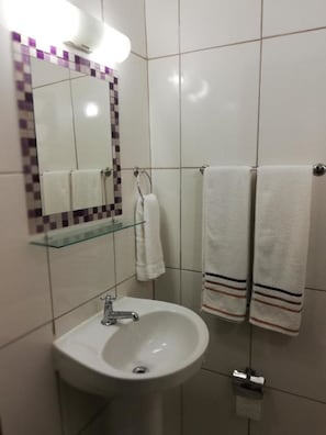 Chuveiro, toalhas de banho, sabonete, papel higiênico