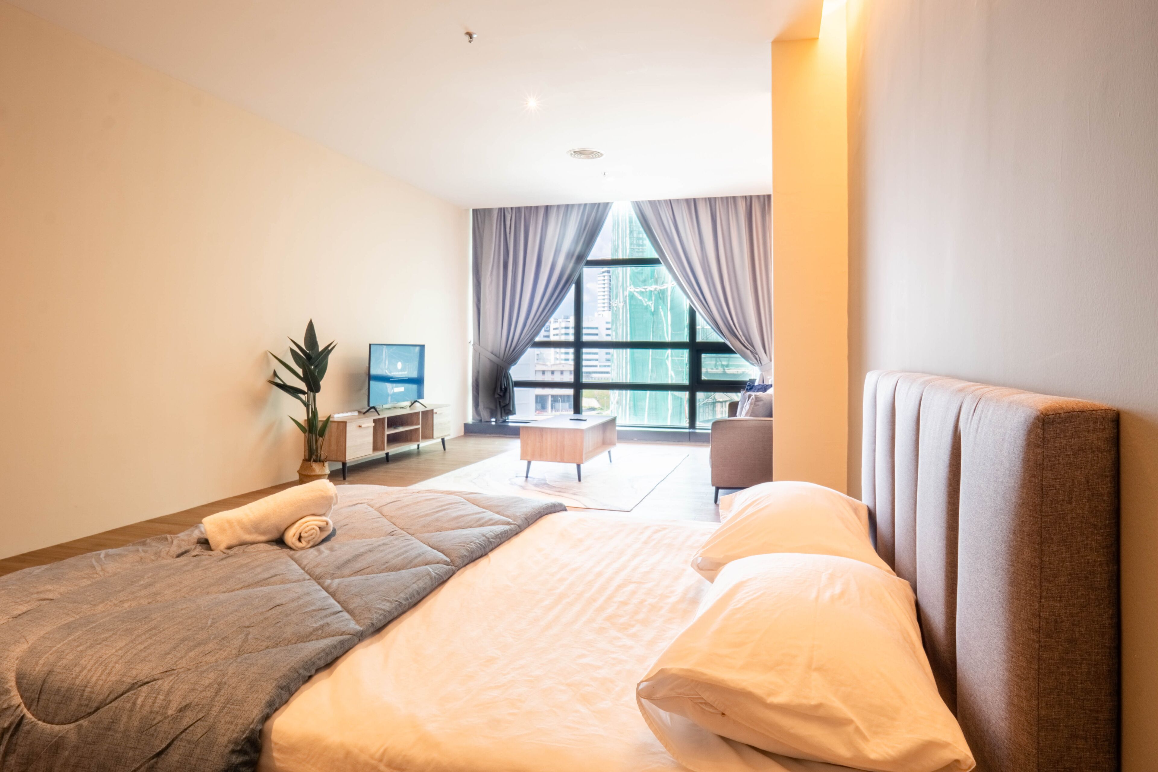 Moderni hotellihuone, jossa on suuri sänky, työpöytä, tuoli ja televisio.