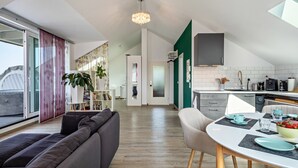 A modern living space with a sofa, dining table, and kitchen area.