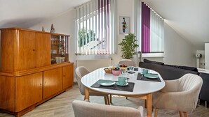 A dining area with a round table, chairs, a wooden cabinet, and a staircase.
