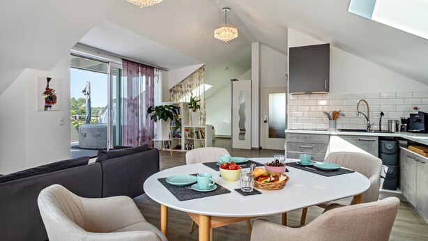 A modern kitchen with white cabinets, a built-in oven, and a large window.