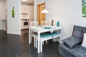A modern kitchen with white cabinets, a dining table set with plates, glasses, and a bottle.