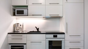 Eine moderne Küche mit integrierten Geräten, darunter eine Mikrowelle, ein Backofen und eine Kaffeemaschine.