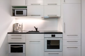 Une cuisine moderne dotée d’appareils électroménagers intégrés, notamment un four à micro-ondes, un four et une machine à café.