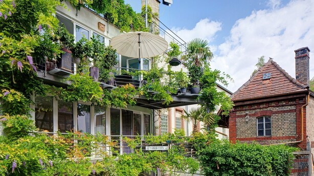 Ein Gebäude mit einem Balkon, einem hängenden Sonnenschirm und einem Ziegelkamin.