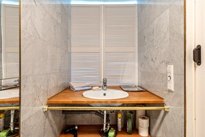 Une salle de bain avec un meuble-lavabo en bois, un lavabo blanc, un miroir et un porte-serviettes.