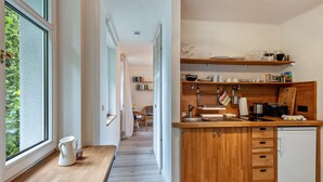 Een moderne keuken met houten kastjes, een ingebouwde vaatwasser en een raam met uitzicht op groen.
