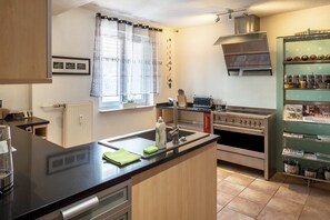 Une cuisine moderne avec un plan de travail noir, des appareils en acier inoxydable et une fenêtre agrémentée de rideaux légers.