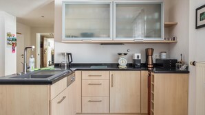 A compact kitchen with a sink, cabinets, a coffee maker, and a scale.