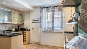 A modern kitchen with a built-in oven, a coffee machine, and a window with a decorative curtain.